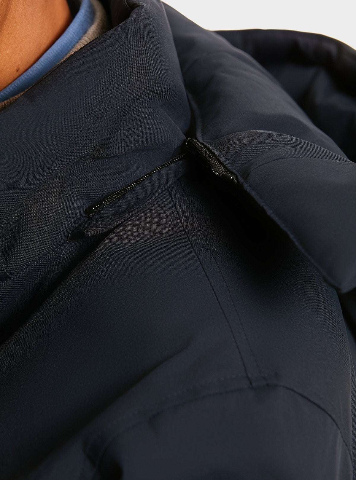 Detailansicht der langen Herrenjacke wasserdicht mit abnehmbarer Kapuze in Dunkelblau, ideal für regnerische Tage. Reißverschluss an der Kapuze sichtbar.